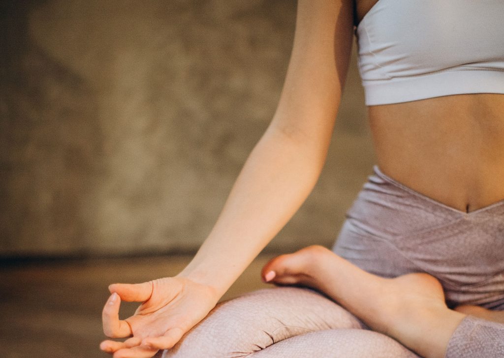 Donna in posizione meditativa con gambe incrociate e dita unite - esercizi yoga prima di dormire